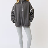 Woman wearing a gray hoodie with white accents and leggings on a white background