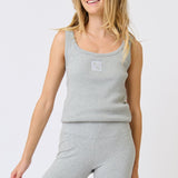 Woman wearing a gray tank top and leggings on a white background